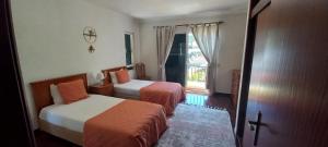 莫尼兹港Costa Azul的酒店客房设有两张床和窗户。