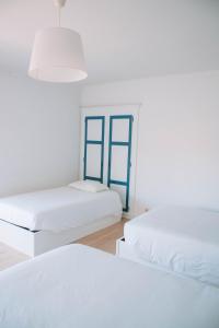 卡米尼亚Arca Nova Guest House & Hostel Caminha的白色客房的两张床,设有蓝色窗户