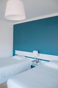 卡米尼亚Arca Nova Guest House & Hostel Caminha的蓝色墙壁客房的两张床
