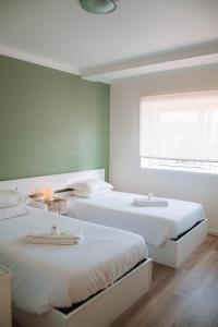 卡米尼亚Arca Nova Guest House & Hostel Caminha的一间卧室设有两张床和窗户。