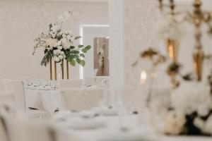 NevesinjeSvadbeni salon i prenoćište MILANOVIĆ的一间设有白色桌子和白色椅子及鲜花的房间
