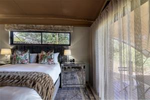 侯斯普瑞特Oase by 7 Star Lodges - Greater Kruger Private 530ha Reserve的一间卧室设有两张床和大窗户