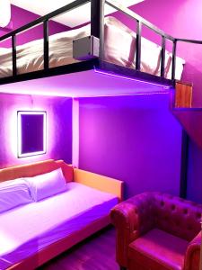 新加坡Arena eSports Hotel @ Bugis Village的紫色客房配有一张双层床和一张沙发