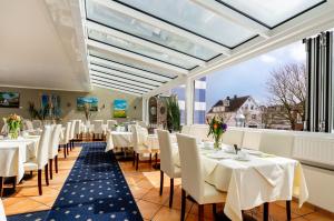 韦斯特兰冯斯蒂芬酒店的餐厅设有白色的桌椅和大窗户