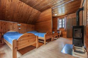 GoreljekMala koča Wooden Cabin的带三张床和燃木炉的客房