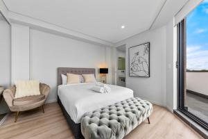 悉尼Elegant and Modern Style Apartments in Dulwich hill的一间卧室配有一张大床和一把椅子