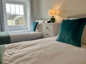米德尔赫姆Wesley Cottage的一间卧室配有两张带绿色枕头的床和窗户。