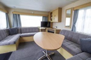 亨斯坦顿6 Berth Caravan For Hire At Manor Park Holiday Park In Norfolk Ref 23025t的客厅配有沙发和桌子