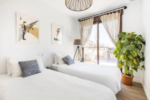 阿桂拉斯Luxury Designer Apartment - Unbeatable Sea Views的白色卧室内的两张床,配有盆栽植物