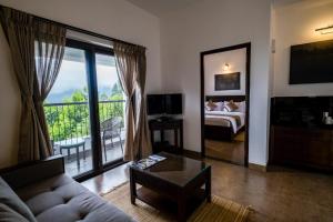 科代卡纳尔Dvara Luxury Resort Kodaikanal的带沙发和床的客厅以及阳台。