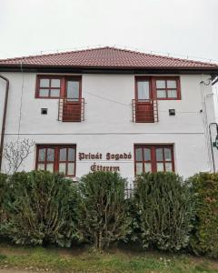 比克克森特凯赖斯特Privát Fogadó és Étterem的白色房子,前方有红色窗户和灌木
