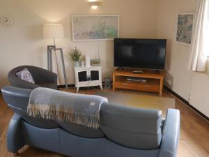 西卢港Talehay Cottages的客厅配有蓝色的沙发和平面电视。