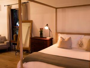 布隆方丹Olyf guestcottage的一间卧室配有一张带灯和椅子的天蓬床