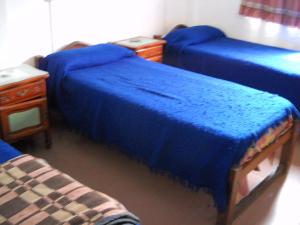 蒙特格兰德Hotel Aeropuerto Monte Grande的一间设有三张蓝色的床和一张桌子的房间
