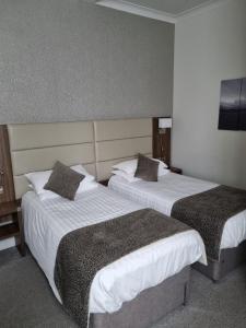 威灵堡雌鹿酒店的配有2张床铺的酒店客房,提供白色床单和枕头