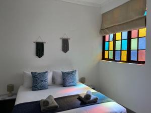 普利登堡湾Forest Gate Estate的一间卧室配有一张带五颜六色窗户的床