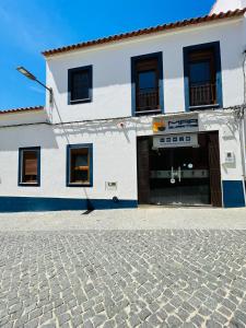 米尔芳提斯城Só Mar的一条白色的建筑,有门,一条鹅卵石街道