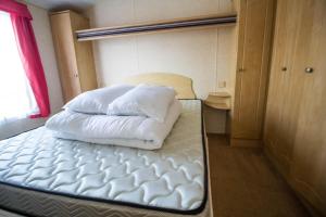 亨斯坦顿6 Berth Pet Friendly Static Caravan By Hunstanton Beach Ref 13011l的一张床上有两个枕头的房间