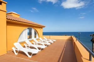 圭马尔港Dúplex La Marea的一张白色椅子坐在俯瞰大海的阳台上