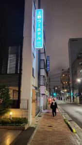 东京Ueno Woo Hotel的沿着建筑物旁边的街道走的人