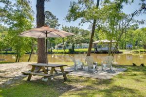 ElbertaWaterfront Foley Area Home - 15 Mi to Gulf!的树旁的野餐桌和椅子,带雨伞