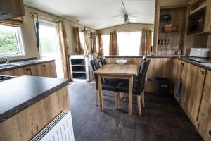 萨克斯曼德姆4 Berth Caravan With Decking And Wifi At Carlton Meres In Suffolk Ref 60010k的一个带桌椅的大篷车的厨房