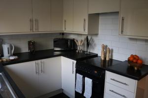 诺丁汉Charming 2 Bed House - Family Friendly的厨房配有白色橱柜和黑色台面