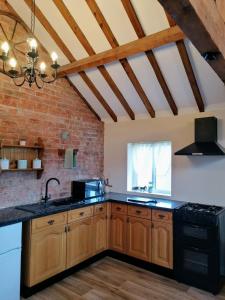 伍德哈尔温泉水疗Poplar Cottage的厨房配有木制橱柜和砖墙
