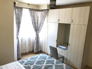 内罗毕Maliaways Comfy Airbnb-Jkia的一间卧室配有一张床、一张书桌和一个窗户。