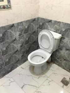 十月六日城استوديو的浴室设有白色卫生间,位于瓷砖墙壁上