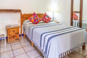 瓦哈卡市波萨达德尔中心酒店的一间卧室配有一张大床,床上配有色彩缤纷的枕头