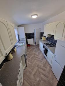 盖茨黑德Luna Apartments Newcastle Gateshead 1的厨房铺有木地板,配有白色橱柜。