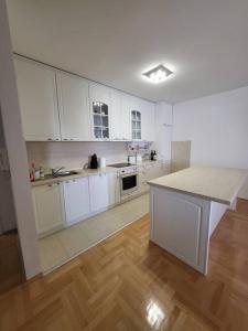 斯特鲁米察Luxury Central Apartment的一间铺有木地板的大厨房,配有白色的橱柜