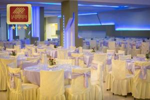 瓦努科La Estancia Hotel的宴会厅配有白色的桌子和白色的椅子
