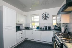 米尔盖Cosy & Central 2BD Apartment Milngavie, Glasgow的厨房配有白色橱柜和炉灶。