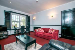 米尔盖Cosy & Central 2BD Apartment Milngavie, Glasgow的客厅配有红色的沙发和桌子