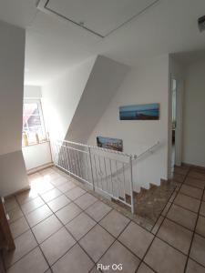 胡苏姆Nordseehaus Husum mit Fahrrädern的客房拥有白色的墙壁和瓷砖地板,设有楼梯。