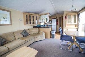 亨斯坦顿6 Berth Pet Friendly Caravan By Hunstanton Beach, Norfolk Ref 13012l的带沙发和桌子的客厅以及厨房。