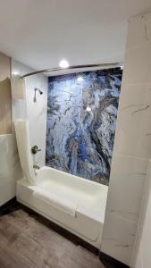 弗洛伦斯Budget Inn的浴室配有浴缸,墙上挂有绘画作品