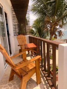 RincónHotel Casa Sattva- Bed & Breakfast的棕榈树门廊上的木椅