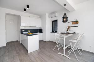 沃迪切Apartments Slavica的厨房配有白色橱柜和桌椅