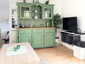 卢恩斯基尔Holiday home LJUNGSKILE VI的客厅里绿色的橱柜,配有桌子