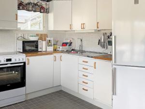 卢恩斯基尔Holiday home LJUNGSKILE VI的厨房配有白色橱柜和白色冰箱。