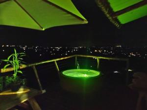 ChinchináGlamping Orosierra的晚间在阳台上设有绿色浴缸的浴室
