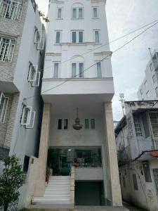 胡志明市MơMơ Residence的前面有楼梯的高大的白色建筑