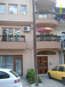 斯特鲁加Jovanoski Apartments的停在大楼前的黄色汽车,带雨伞
