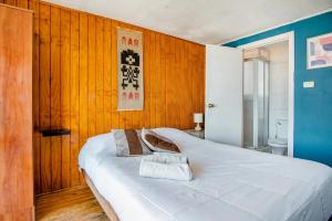瓦尔帕莱索Casa Altavista的一张白色大床,位于带木墙的房间