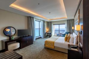 富查伊拉Al Bahar Hotel & Resort的酒店客房,配有床和电视