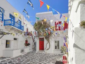 米克诺斯城The Sunday House in the heart of Mykonos Town的一条有旗帜和红色门的狭窄街道