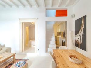 米克诺斯城The Sunday House in the heart of Mykonos Town的一间带木桌的客厅和一间厨房